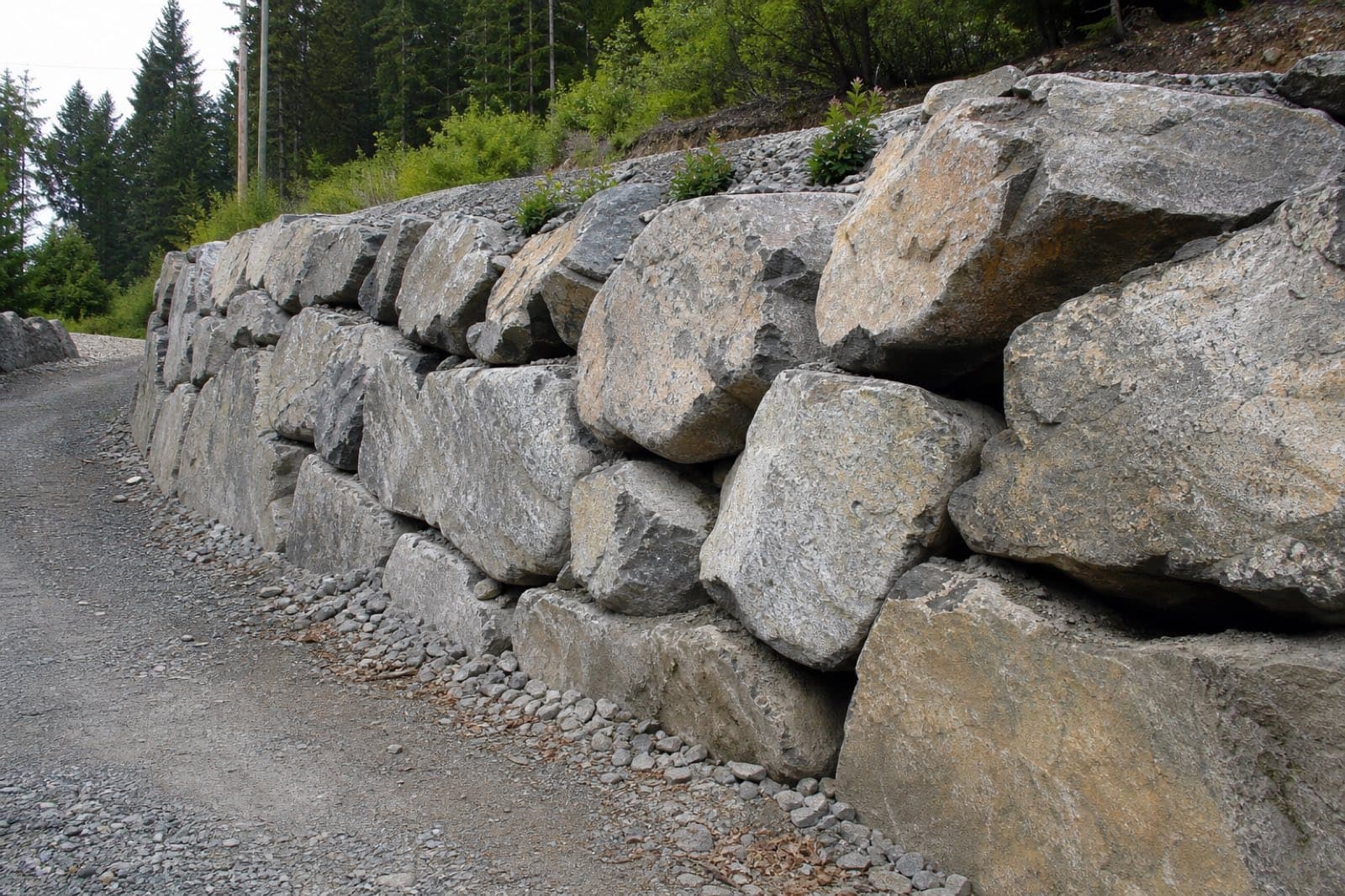 Tall armour stone retaining wall holding a steep Fraser Valley grade